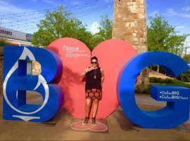 A woman stands in front of a heart statue