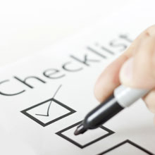 Checklist with a person using a black marker to check the boxes.